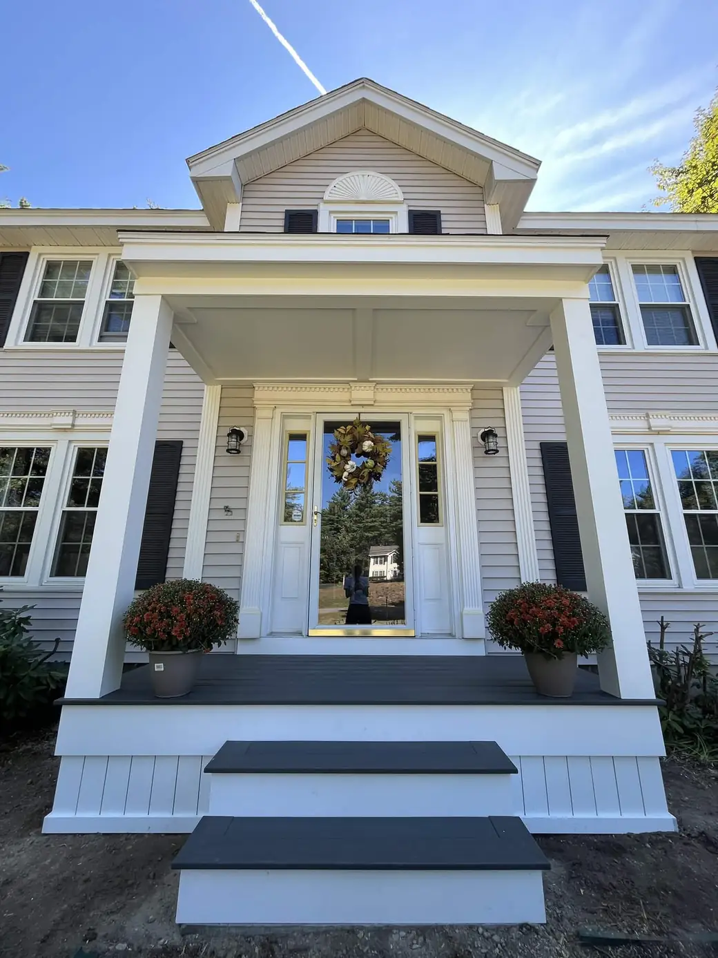 Colonial portico with white columns, dentil trim and a composite deck at the front door