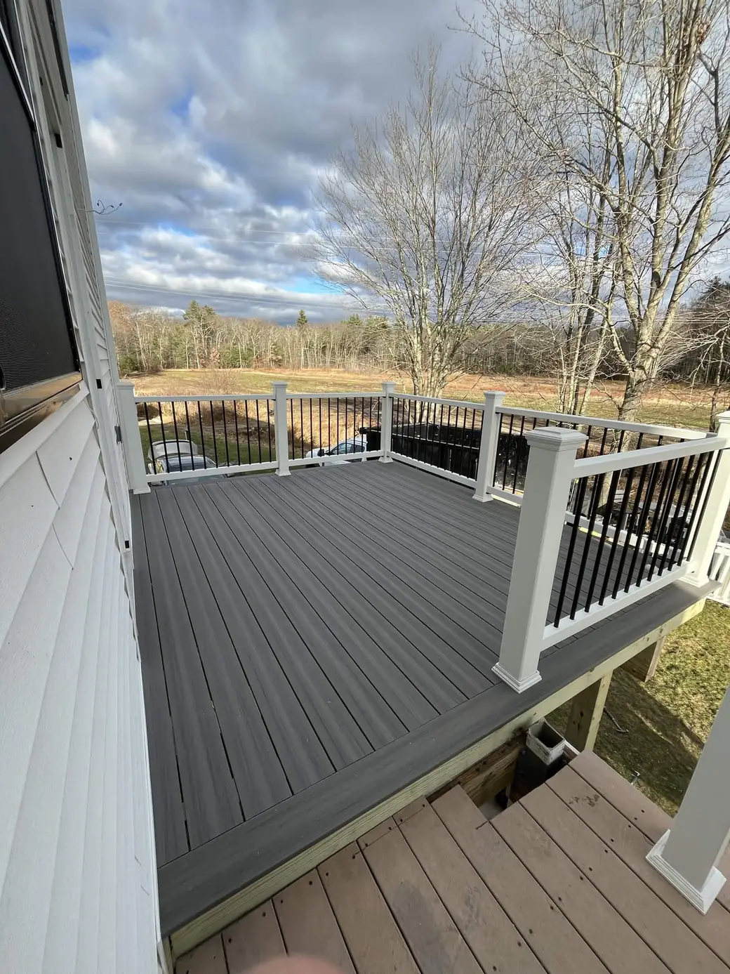 Grey composite deck with white railing overlooking an open field