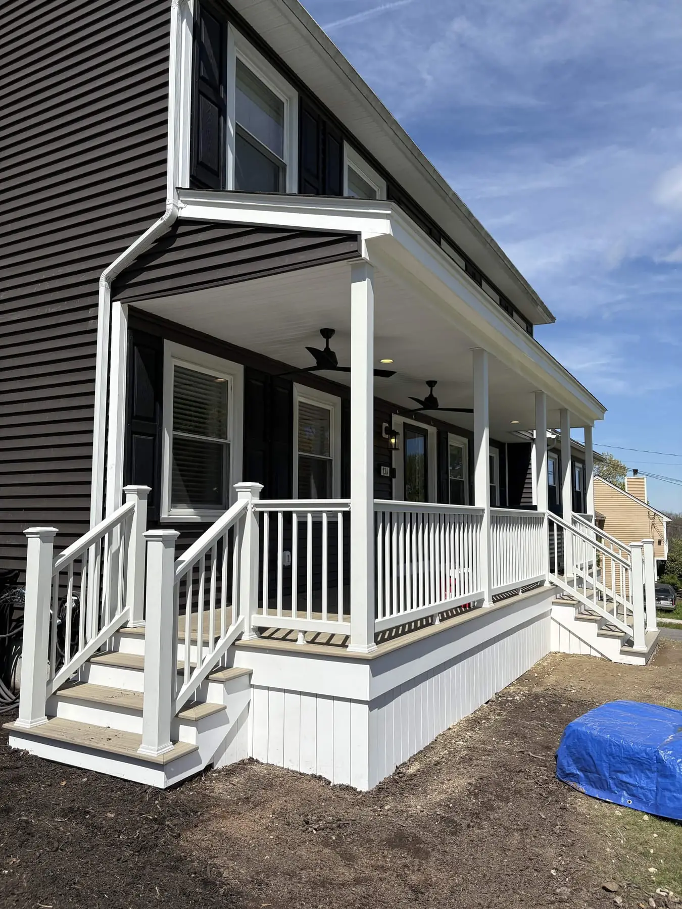 Farmer's porch under blue sky with two black ceiling fans mounted in the beadboard ceiling