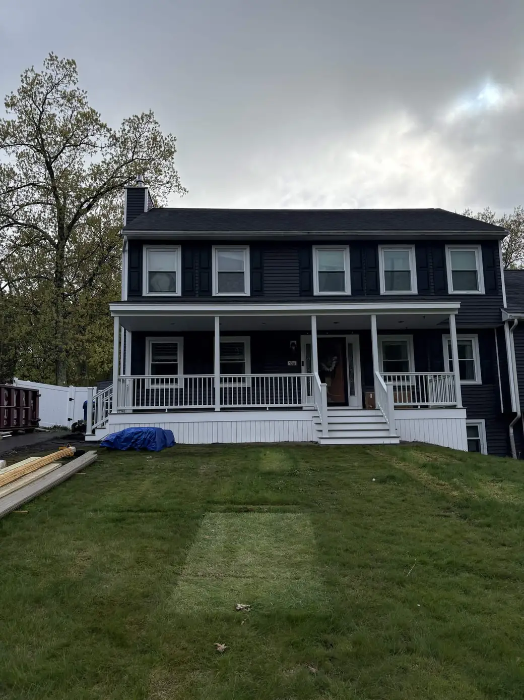 Full front elevation of a charcoal two-storey colonial with a new full-width farmer's porch, white columns and white railings
