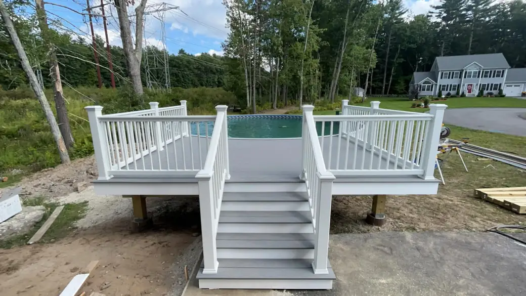 White vinyl-railed pool deck with centre stairs surrounding an above-ground pool