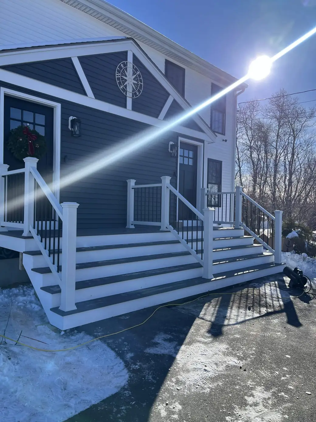 Wide composite entry stairs with white railings below a navy gable with a sunburst detail
