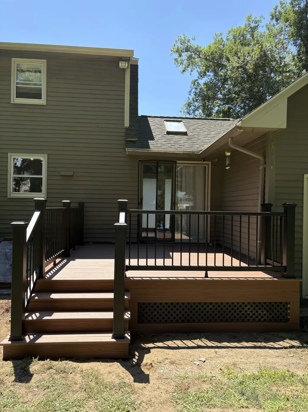 Backyard composite deck with a black aluminium railing and a lattice skirt below