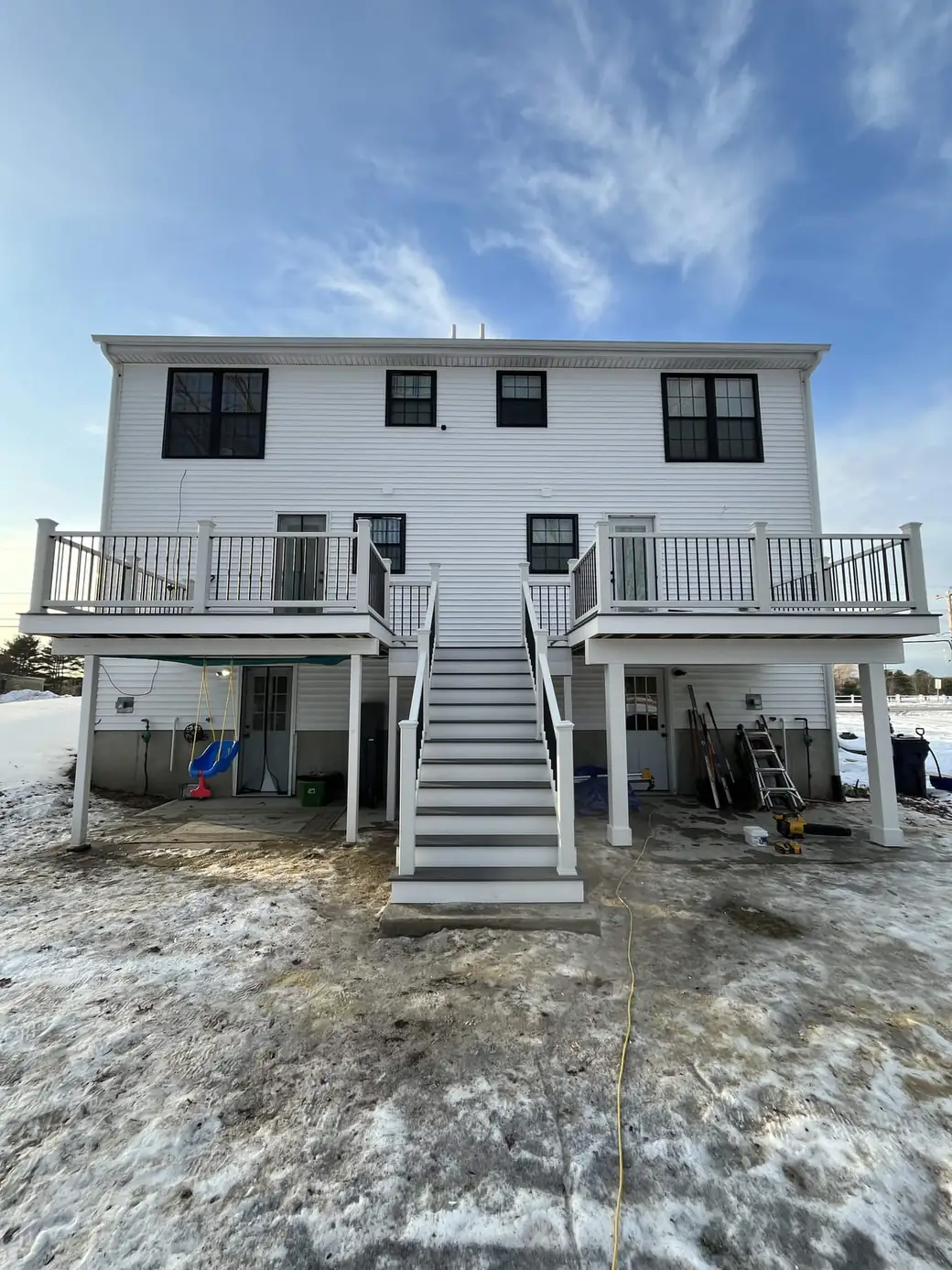 Rear elevation of a two-family home with matching raised decks either side of a centre stair